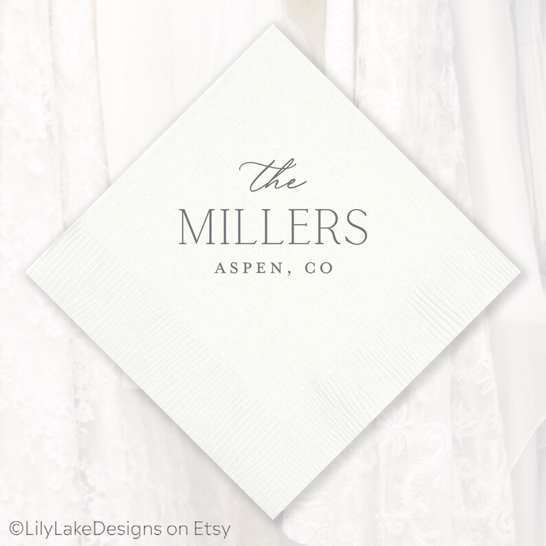 Puede incluir: Una servilleta cuadrada blanca con una superficie texturizada. El texto "The MILLERS ASPEN, CO" est&aacute; impreso en gris con fuente cursiva y sans-serif. La servilleta es probablemente para una boda o evento especial.