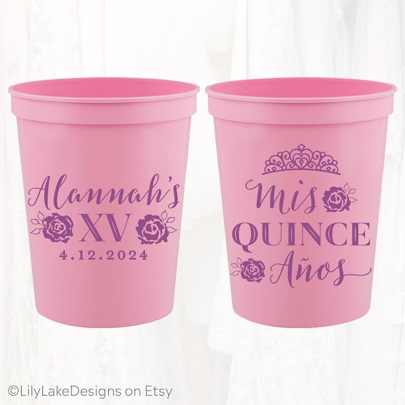 May include: Two pink plastic cups with purple text and designs. One cup says "Alannah's XV 4.12.2024" and the other says "Mis Quince A&ntilde;os" with a crown design.