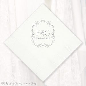 Puede incluir: Servilleta de papel cuadrada blanca con superficie texturizada. La servilleta presenta un dise&ntilde;o de corona floral gris con las iniciales "F&G" y la fecha "08.14.2025" en el centro. El nombre de la tienda Etsy "LilyLakeDesigns on Etsy" est&aacute; en la parte inferior.