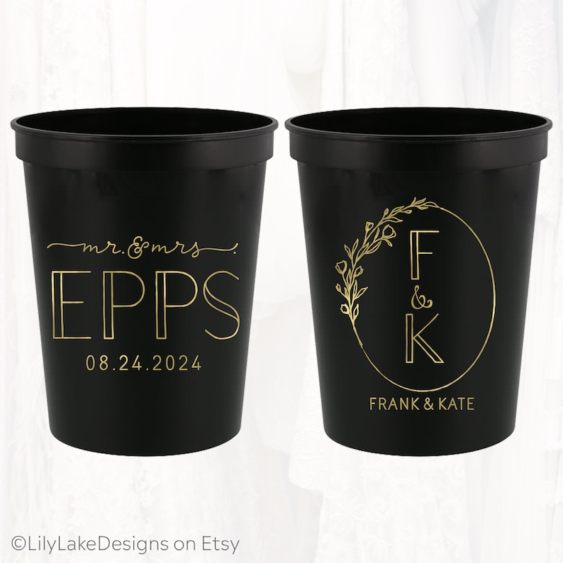 May include: Two black plastic cups with gold lettering. One cup says "mr. & mrs. EPPS 08.24.2024". The other cup has a floral design with the letters "F & K" inside a circle and the text "FRANK & KATE" below.