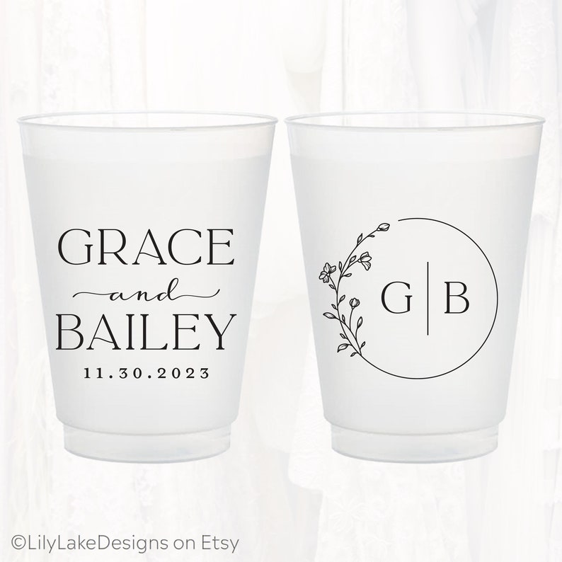 Pu&ograve; includere: Due bicchieri in plastica satinata con testo e grafiche stampate in nero. Un bicchiere mostra i nomi GRACE e BAILEY con la data 11.30.2023. L'altro bicchiere presenta un disegno a corona floreale circolare attorno alle iniziali G e B.