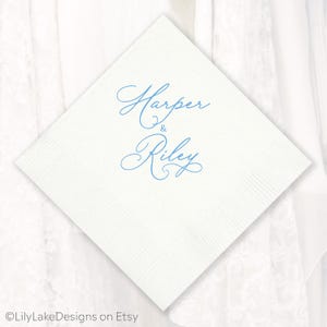 Puede incluir: Servilleta cuadrada blanca con los nombres "Harper & Riley" impresos en azul claro. La servilleta tiene una superficie texturizada, ideal para una boda o evento especial.