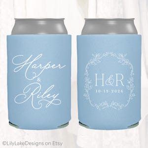 May include: Two light blue can coolers. One cooler has the names "Harper & Riley" in white script. The other has the initials "H&R" inside a white floral wreath, with the date "10.15.2026" below. The Etsy shop name "LilyLakeDesigns" is at the bottom.