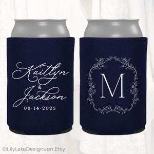 May include: Navy blue can coolers with white text. One cooler features the names "Kaitlyn & Jackson" and the date "08.14.2025". The other has a white floral wreath around the letter "M".