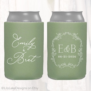 May include: Two green can coolers with silver tops. One cooler has the names "Emily & Bret" in white script. The other has "E&B" inside a floral wreath and the date "06.21.2026".