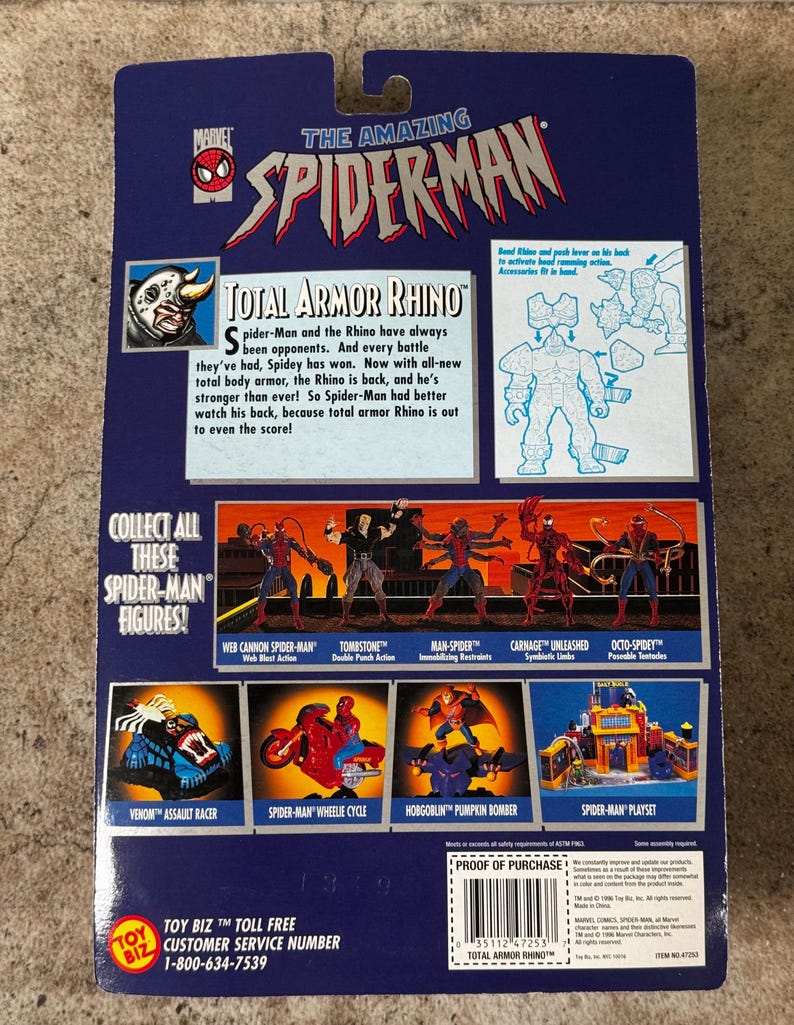 Puede incluir: La parte trasera de un paquete de figuras de acci&oacute;n vintage de Spider-Man. El paquete presenta el texto "Total Armor Rhino" e im&aacute;genes de otras figuras y juegos de Spider-Man. El logotipo de Marvel es visible.