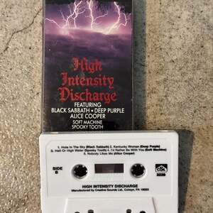 May include: A vintage cassette tape for "High Intensity Discharge" featuring Black Sabbath, Deep Purple, and Alice Cooper. The cassette has a white body with track listings and a black case with a lightning storm graphic.