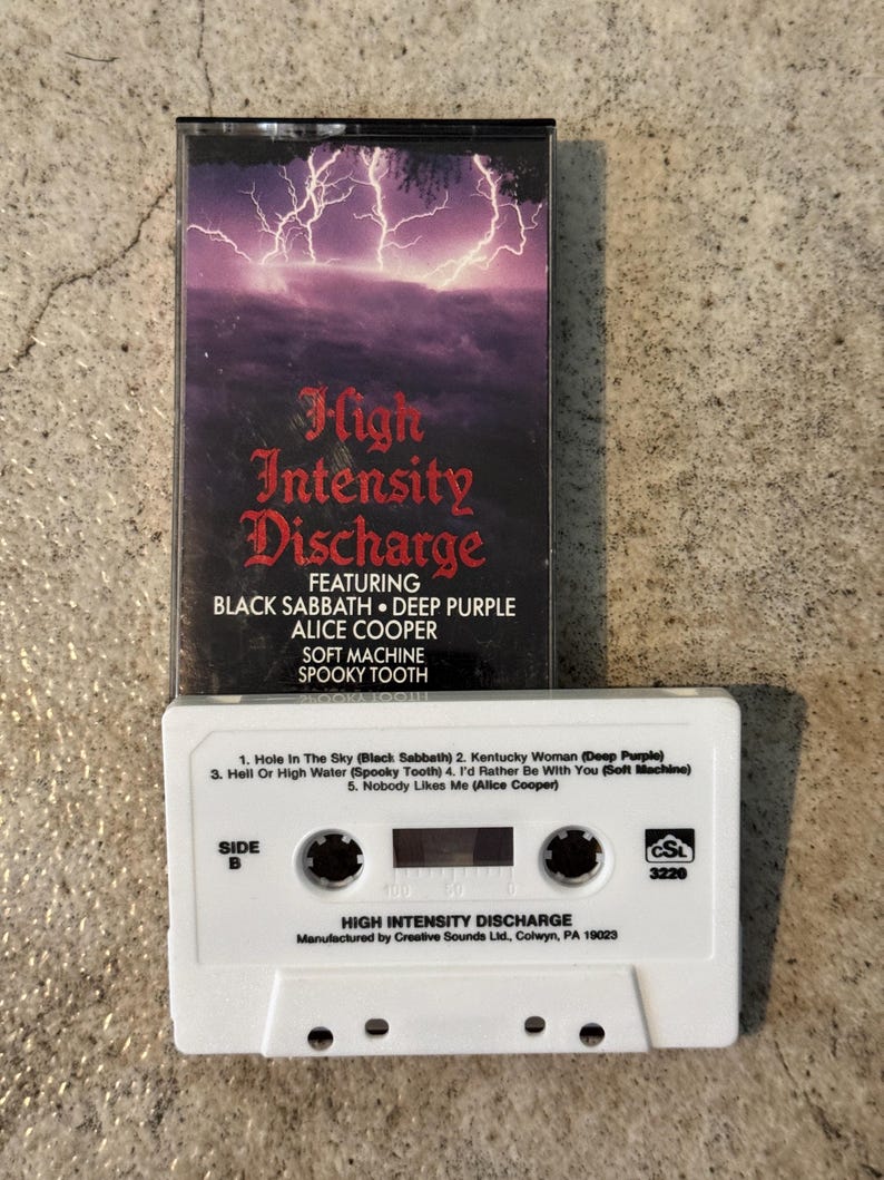 May include: A vintage cassette tape for "High Intensity Discharge" featuring Black Sabbath, Deep Purple, and Alice Cooper. The cassette has a white body with track listings and a black case with a lightning storm graphic.