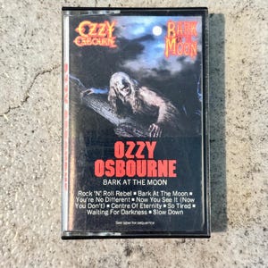 May include: A vintage cassette tape for Ozzy Osbourne's "Bark at the Moon" album. The cover displays a monster graphic and the artist's name in red. Song titles are listed on the bottom of the cassette.