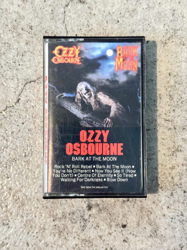 May include: A vintage cassette tape for Ozzy Osbourne's "Bark at the Moon" album. The cover displays a monster graphic and the artist's name in red. Song titles are listed on the bottom of the cassette.