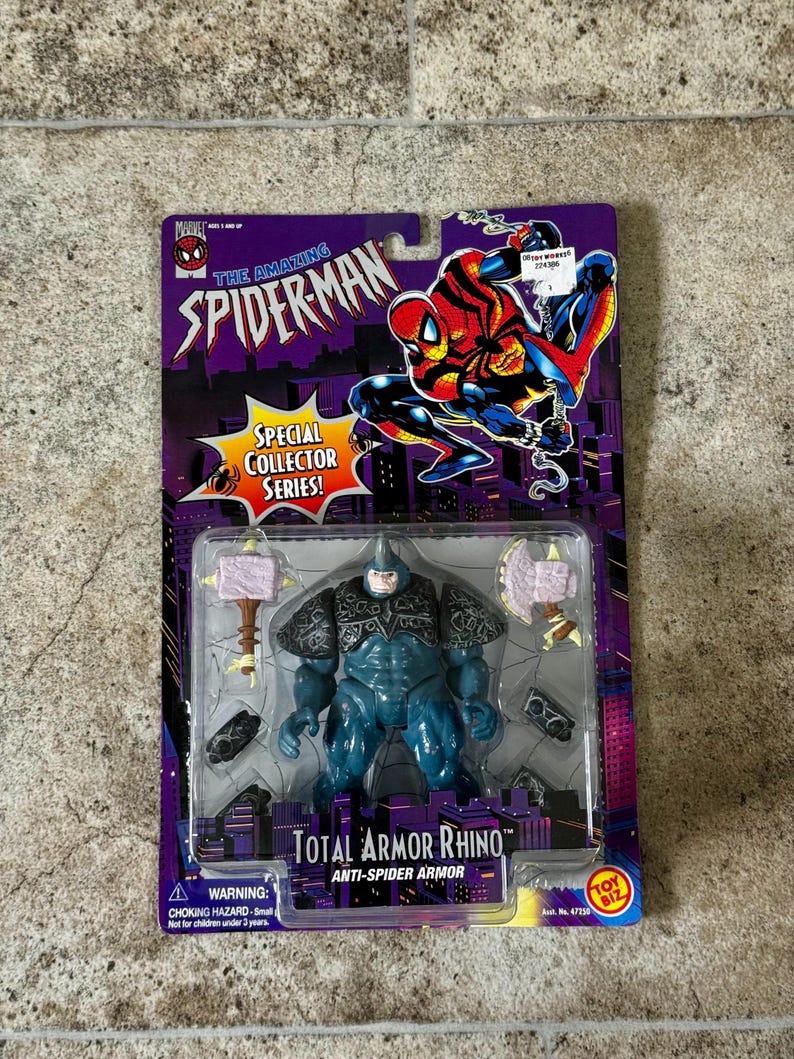 Puede incluir: Figura de acci&oacute;n sellada de Total Armor Rhino de la serie Spider-Man Special Collector. La figura es azul con armadura gris y viene con dos armas en forma de martillo. El embalaje presenta ilustraciones de Spider-Man y el logotipo de Toy Biz.