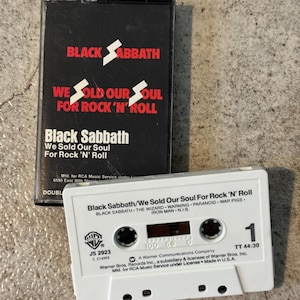May include: A Black Sabbath cassette tape and case. The black case features the band's name and album title in red and white. The white cassette has black text, including song titles and the Warner Bros. logo. A retro music item.