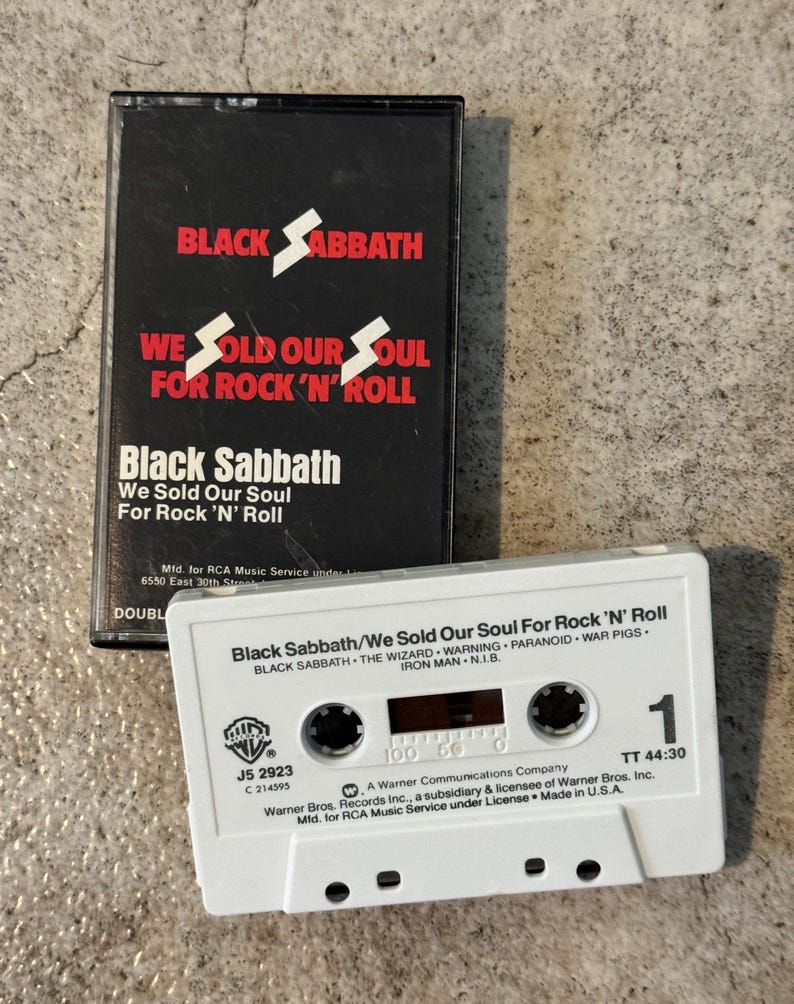 May include: A Black Sabbath cassette tape and case. The black case features the band's name and album title in red and white. The white cassette has black text, including song titles and the Warner Bros. logo. A retro music item.