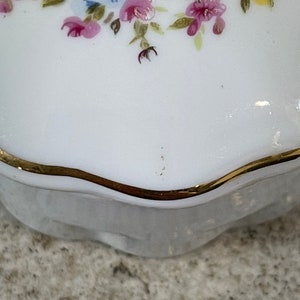 Op de afbeelding: Wit porseleinen sieraden doosje met een gouden rand en een bloemenontwerp met roze, gele en blauwe bloemen.
