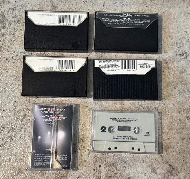 May include: A selection of vintage cassette tapes, featuring black and white designs. The labels display band names and song titles. The image is captured from a top-down angle, showcasing the tapes' details.
