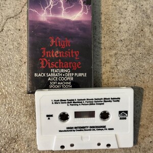 May include: A vintage cassette tape for "High Intensity Discharge" featuring Black Sabbath, Deep Purple, and Alice Cooper. The cover has a purple lightning storm design. The white cassette tape lists song titles.