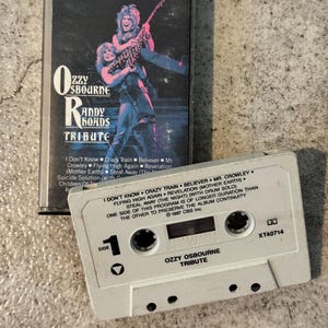 May include: A vintage cassette tape of the Ozzy Osbourne Randy Rhoads Tribute album. The cassette case features a colourful image of the musicians. The white cassette tape has the album title and song list printed on it. The album was released in 1987.