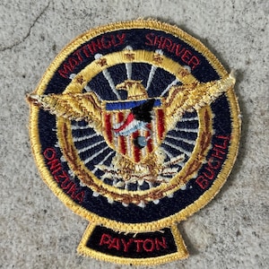 May include: Embroidered patch with a circular design featuring gold wings, a central emblem with red, white, and blue stripes, and the names MATTINGLY, SHRIVER, ONIZUKA, and BUCHLI. The name PAYTON is at the bottom.