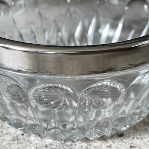 K&ouml;nnte beinhalten: Eine klare Glassch&uuml;ssel mit silbernem Rand. Die Sch&uuml;ssel hat ein dekoratives Muster aus kleinen, erhabenen Kreisen.