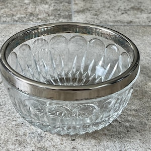 K&ouml;nnte beinhalten: Eine klare Glassch&uuml;ssel mit silbernem Rand. Die Sch&uuml;ssel hat ein Diamantenmuster und ist perfekt zum Servieren von Snacks oder Desserts.
