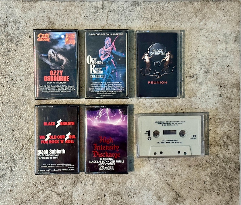 May include: A selection of six vintage cassette tapes featuring rock and heavy metal artists. The tapes include albums by Ozzy Osbourne, Black Sabbath, and a tribute album. The cassette cases are black and white with album art.