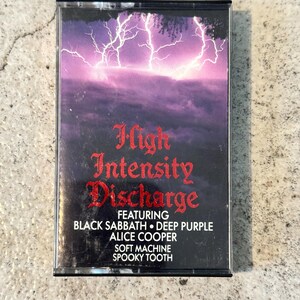 May include: A retro cassette tape with a purple and black cover featuring a lightning storm graphic. The title "High Intensity Discharge" is in red gothic lettering, with artist names like Black Sabbath and Alice Cooper.