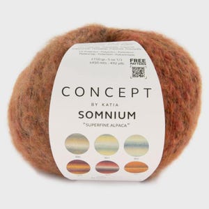 Peut inclure: Pelote de laine Concept by Katia Somnium en alpaga superfine, aux tons bruns et orangés. L'étiquette indique 150 g et 450 mètres. Le texte "FREE PATTERN" est également présent sur l'étiquette.