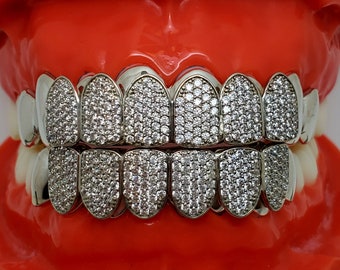 Puede incluir: Un juego de dientes chapados en oro con un diseño completo de diamantes. Los dientes están colocados en un molde de plástico rojo.