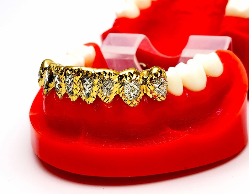 May include: Gold grill with diamond accents on a red plastic model of a mouth.