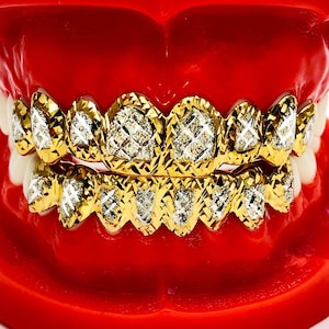May include: Gold grill with diamond-shaped accents. The grill is displayed on a red plastic model of a mouth.