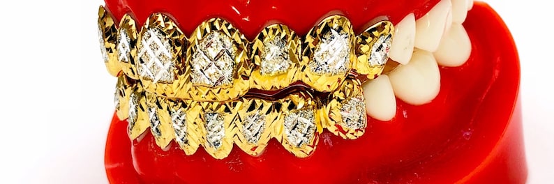 May include: A gold grill with diamond-shaped stones set in a textured gold frame. The grill is shown on a red and white model of a mouth.