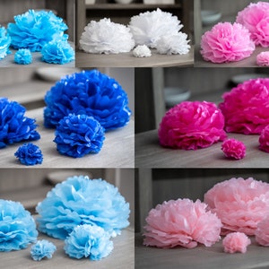 May include: Assortment of tissue paper pom-poms in various sizes and colors, including blue, pink, and white. The pom-poms are arranged in groups of three, with the largest pom-pom in the center and the two smaller pom-poms on either side.