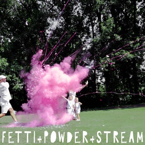 May include: A group of people celebrating with pink confetti powder and streamers. A man in a white shirt is swinging a golf club, releasing the pink powder into the air. The powder creates a large pink cloud. The people are smiling and laughing. CONFETTI + POWDER + STREAMERS is written in white letters at the bottom of the image.