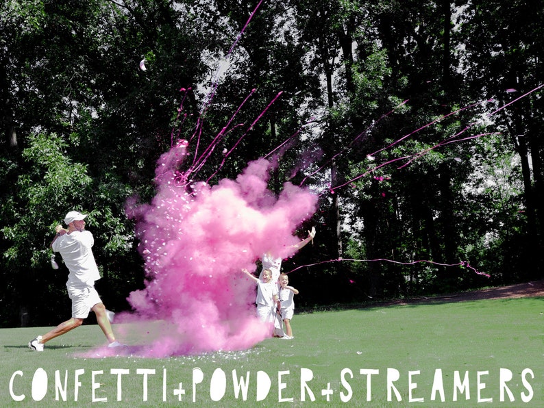 May include: A group of people celebrating with pink confetti powder and streamers. A man in a white shirt is swinging a golf club, releasing the pink powder into the air. The powder creates a large pink cloud. The people are smiling and laughing. CONFETTI + POWDER + STREAMERS is written in white letters at the bottom of the image.