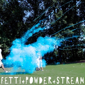 May include: A person swings a golf club, releasing blue confetti powder and streamers in the air. The powder creates a large blue cloud, and the streamers are visible against the green grass and trees in the background. The text "CONFETTI + POWDER + STREAMERS" is printed at the bottom of the image.