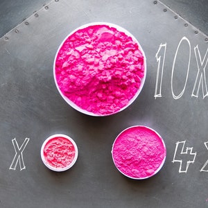May include: Three containers of pink powder, labeled 10x, x, and 4x. The containers are on a gray metal surface.