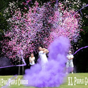 May include: A group of people are standing on a golf course, holding purple and pink confetti cannons. One person is swinging a golf club, and a large purple golf ball is in the air. The text "24" Blush/Pink/Purple Cannons" is visible at the bottom left of the image. The text "XL Purple Golf Ball" is visible at the bottom right of the image.