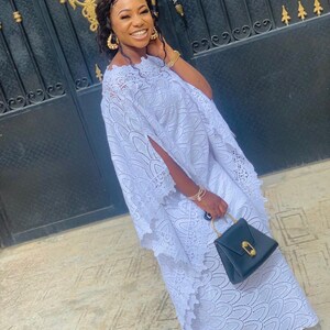 May include: A white lace dress with a long, flowing skirt and a loose-fitting top. The dress has a delicate, intricate pattern and is perfect for a special occasion.