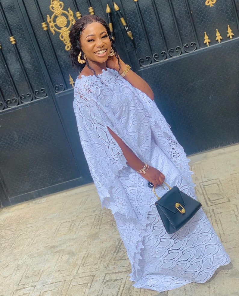 May include: A white lace dress with a long, flowing skirt and a loose-fitting top. The dress has a delicate, intricate pattern and is perfect for a special occasion.
