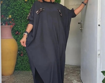 Puede incluir: Un vestido maxi negro de manga larga y cuello alto. El vestido tiene adornos de lentejuelas en los hombros.