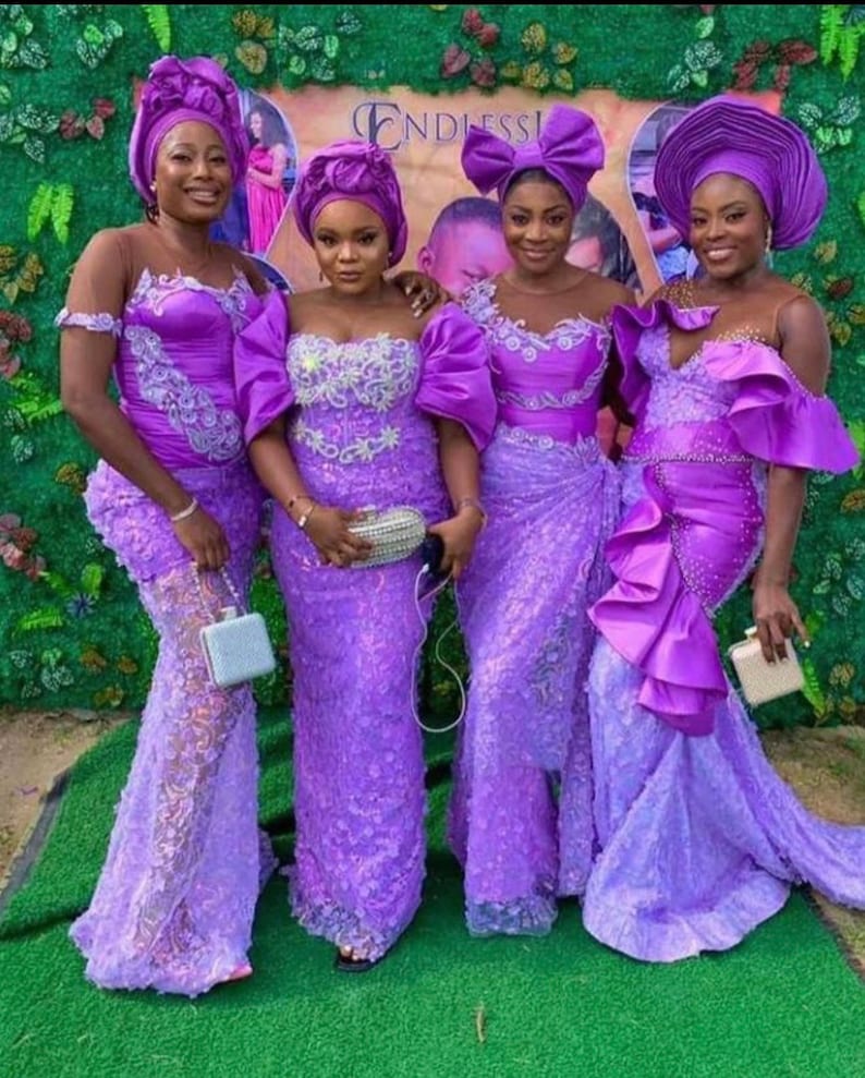 Puede incluir: Cuatro mujeres con vestidos de encaje morado a juego y turbantes a juego. Los vestidos tienen un corpi&ntilde;o ajustado y una falda fluida. Las mujeres est&aacute;n de pie frente a un fondo verde con la palabra "Endless" visible.