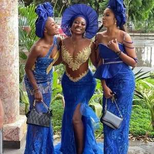 Puede incluir: Tres mujeres con vestidos de encaje azul y dorado y turbantes a juego. Las mujeres est&aacute;n de pie juntas y sonriendo. Todas llevan peque&ntilde;os bolsos negros.