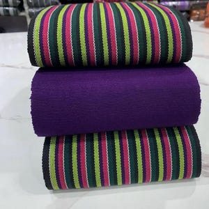 May include: Three rolls of fabric, one purple and two with black, green, pink, and white stripes.