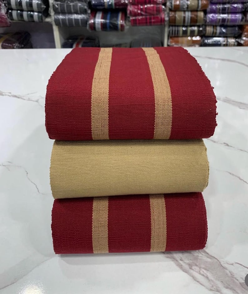 May include: Three rolls of fabric with alternating red and beige stripes. The fabric is woven and has a textured surface.