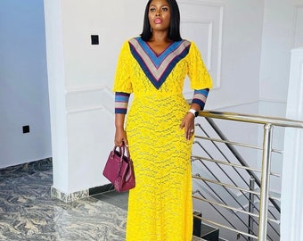 May include: A yellow lace maxi dress with a blue and white striped neckline and matching striped cuffs. The dress has a fitted bodice and a flowing skirt.