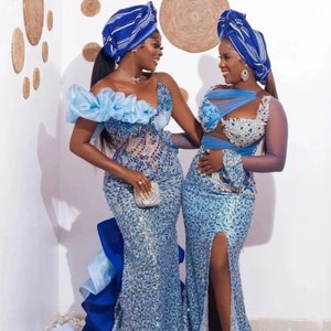 Puede incluir: Dos mujeres con vestidos a juego de lentejuelas azules y plateadas con un turbante azul y blanco. Los vestidos tienen una silueta de sirena y uno de los vestidos tiene una abertura en el muslo.