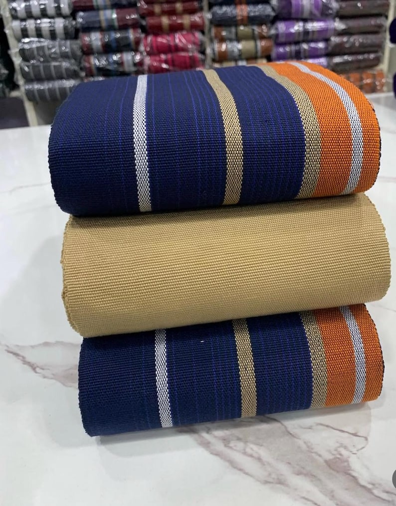 May include: Three rolls of fabric with striped patterns in blue, beige, and orange. The fabric is folded and stacked on top of each other.