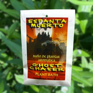 May include: A white packet with a red, yellow, and black graphic design. The text on the packet reads "Espanta Muerto" and "Ghost Chaser Plant Bath".