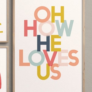 May include: A framed print with the words "Oh How He Loves Us" in a colorful, layered font design. The letters are in shades of pink, red, yellow, blue, and green.