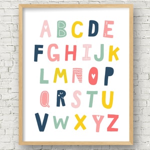 May include: A colorful alphabet poster with each letter in a different color and design. The letters are arranged in alphabetical order and are surrounded by a white background. The poster is framed in a light wood frame.
